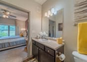 Thumbnail 8 of 21 - a bathroom with a sink and a mirror and a bed