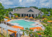 Thumbnail 1 of 21 - a swimming pool with orange umbrellas in front of a house