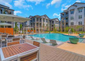 Thumbnail 1 of 50 - an outdoor pool with tables and chairs at an apartment building
