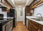 Thumbnail 4 of 9 - A kitchen with dark wood cabinets and stainless steel appliances.