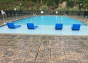 Thumbnail 11 of 17 - A pool surrounded by blue chairs and a black fence.