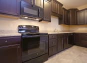 Thumbnail 2 of 18 - a kitchen with dark wood cabinets and black appliances