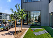 Thumbnail 55 of 58 - A modern building with a grey exterior and a small garden area in front.