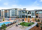 Thumbnail 31 of 58 - A modern apartment complex with a pool and landscaped grounds.