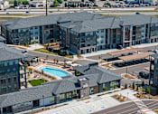Thumbnail 23 of 58 - A large apartment complex with a pool and a covered walkway.