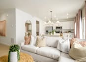 Thumbnail 15 of 24 - A living room with a white couch and a potted plant on a yellow rug.