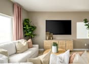 Thumbnail 14 of 24 - A living room with a white couch, a flat screen TV, and a potted plant.