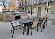 Thumbnail 11 of 12 - a patio with a table and chairs and a grill