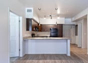 Thumbnail 1 of 25 - A kitchen with a white island and a black refrigerator.