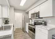 Thumbnail 3 of 29 - A kitchen with white cabinets and stainless steel appliances.