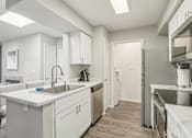 Thumbnail 1 of 29 - A modern kitchen with white cabinets and stainless steel appliances.