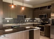 Thumbnail 4 of 23 - Modern kitchen with pendant lighting and hexagonal backsplash at Matilda at Lower Greenville Apartments, Dallas, 75206