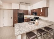 Thumbnail 3 of 25 - A kitchen with a granite countertop and stainless steel appliances.