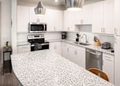 Thumbnail 8 of 25 - Modern kitchen with white cabinets and granite countertops at Avion at West Lemmon Apartments, Dallas, TX 75235
