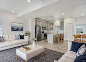 Thumbnail 6 of 22 - a living room and kitchen with a couch and a table