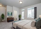 Thumbnail 10 of 14 - A bedroom with a large bed, a dresser, and a window with blinds.