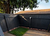Thumbnail 14 of 22 - A backyard with a black fence and a concrete patio.