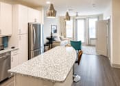 Thumbnail 7 of 25 - Open kitchen island with living area and pendant lighting at Avion at West Lemmon Apartments, Dallas