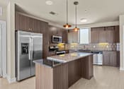 Thumbnail 2 of 23 - Kitchen with island bar and wood grain cabinetry at Matilda at Lower Greenville Apartments, Texas, 75206
