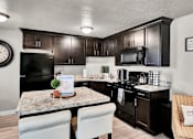 Thumbnail 3 of 12 - a kitchen with black cabinets and a granite counter top