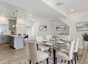 Thumbnail 8 of 22 - A modern dining room with a glass table and white chairs.