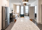 Thumbnail 6 of 25 - Open kitchen with granite island and living area at Avion at West Lemmon Apartments, Dallas, TX 75235