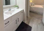 Thumbnail 10 of 25 - a bathroom with a sink and a mirror and a bedroom with a bed