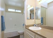 Thumbnail 3 of 12 - A bathroom with a white toilet, sink, and a blue towel.