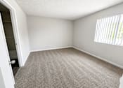 Thumbnail 9 of 22 - A room with a carpeted floor and a window with blinds.