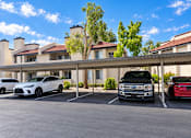 Thumbnail 21 of 23 - Covered parking with residential buildings and trees at Gentrys Walk Apartments, Mesa, Arizona