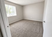 Thumbnail 10 of 22 - A room with a carpeted floor and a window with blinds.