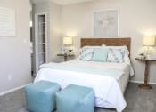 Thumbnail 7 of 25 - a bedroom with a bed and two stools in front of it