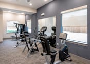 Thumbnail 16 of 25 - Fitness center with cardio equipment and windows at Avion at West Lemmon Apartments, Dallas, TX