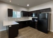 Thumbnail 11 of 14 - a kitchen with black appliances and white counter tops and dark cabinets