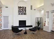 Thumbnail 19 of 24 - A black chair sits in front of a fireplace in a white room.