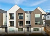 Thumbnail 1 of 24 - A modern residential building with a mix of white and brown exterior.