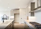 Thumbnail 25 of 28 - A modern kitchen with a white countertop and stainless steel appliances.