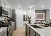 Thumbnail 21 of 24 - A modern kitchen with a stove top oven and a refrigerator.