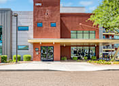 Thumbnail 18 of 24 - A modern building with a red brick facade and a glass entrance.