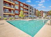Thumbnail 24 of 24 - A large swimming pool in front of apartment buildings.