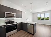 Thumbnail 2 of 6 - A modern kitchen with dark brown cabinets and stainless steel appliances.