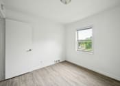 Thumbnail 8 of 26 - A room with a white door and a window with a view of a street.