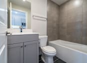 Thumbnail 7 of 8 - A bathroom with a toilet, sink, and bathtub.