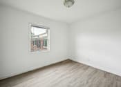 Thumbnail 22 of 26 - A room with a window and wooden flooring.