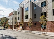 Thumbnail 2 of 11 - A street view of a modern building with a mix of brick and panel facade.