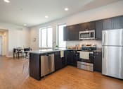 Thumbnail 5 of 11 - A modern kitchen with stainless steel appliances and black cabinets.