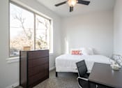 Thumbnail 10 of 11 - A bedroom with a bed, dresser, and desk.