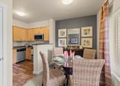 Thumbnail 11 of 12 - a dining room table with chairs and a kitchen in the background