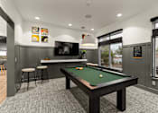 Thumbnail 5 of 15 - A pool table is in the middle of a room with a bar and stools.
