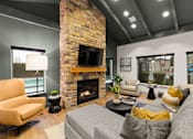 Thumbnail 3 of 15 - A living room with a stone fireplace and a grey couch.